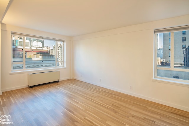 30 E 62nd St Unit 11A, New York City, NY 10065 - empty room with radiator heating unit, baseboards, and wood finished floors