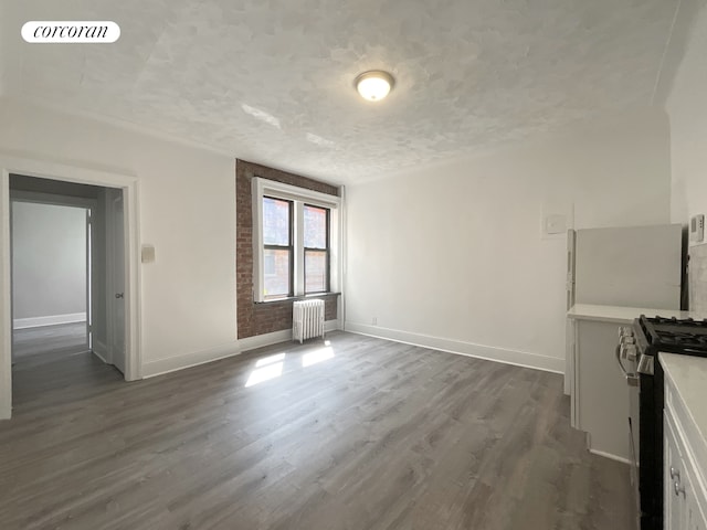 24-75 38th St Unit C9, New York City, NY 11103 - unfurnished dining area with radiator, dark wood-type flooring, and a textured ceiling