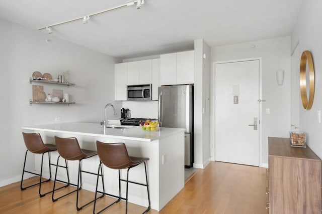 189 Schermerhorn St Unit 16C, New York City, NY 11201 - kitchen with appliances with stainless steel finishes, a sink, a breakfast bar area, white cabinetry, and light wood-style floors