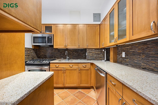 135 W 79th St Unit 1D, New York City, NY 10024 - kitchen featuring appliances with stainless steel finishes, a sink, brown cabinetry, and light stone countertops