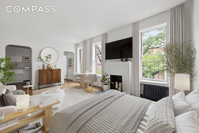 10 Bethune St Unit 2B, New York City, NY 10014 - bedroom with radiator heating unit, arched walkways, multiple windows, and a fireplace