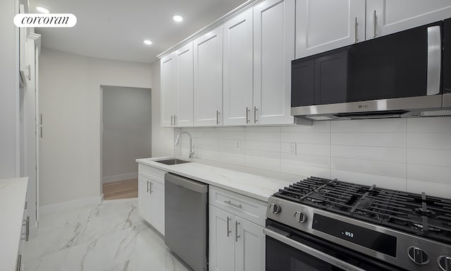 325 E 80th St Unit 1F, New York City, NY 10075 - kitchen featuring appliances with stainless steel finishes, a sink, backsplash, baseboards, and light stone countertops