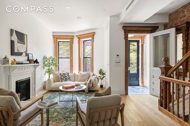 521 Monroe St, New York City, NY 11221 - living room featuring light wood-type flooring, healthy amount of natural light, a fireplace with raised hearth, and baseboards