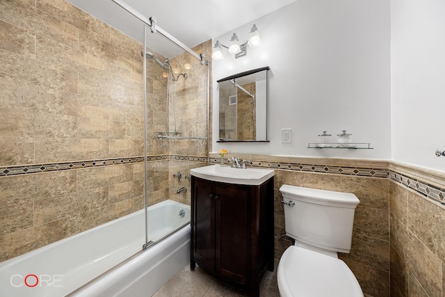 638 Washington St Unit 2B, New York City, NY 10014 - bathroom with tile walls, bath / shower combo with glass door, toilet, vanity, and wainscoting