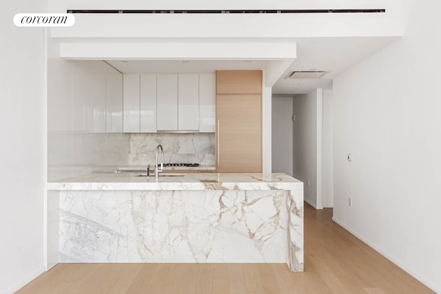 30 Riverside Blvd Unit 20C, New York City, NY 10069 - kitchen featuring modern cabinets, light wood-style flooring, decorative backsplash, a peninsula, and a sink