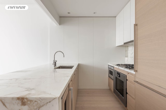 30 Riverside Blvd Unit 20C, New York City, NY 10069 - kitchen featuring a sink, appliances with stainless steel finishes, light wood-style flooring, a peninsula, and light stone countertops