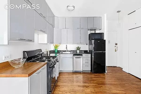 604 Riverside Dr Unit 4E, New York City, NY 10031 - kitchen featuring black appliances, wood finished floors, white cabinets, and dark countertops
