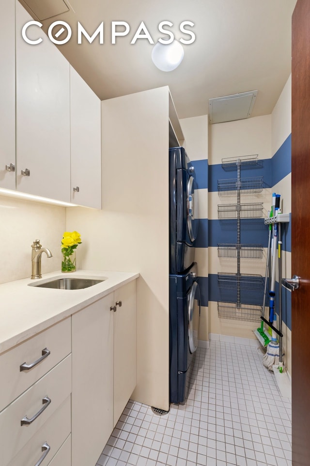 50 W 15th St Unit 2D, New York City, NY 10011 - laundry room featuring stacked washer / drying machine, light tile patterned flooring, and cabinet space