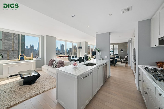 389 E 89th St Unit 27A, New York City, NY 10128 - kitchen featuring a view of skyline, open floor plan, light wood-type flooring, stainless steel gas stovetop, and a kitchen island with sink