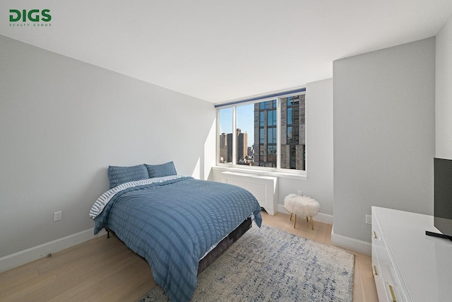 389 E 89th St Unit 27A, New York City, NY 10128 - bedroom featuring light wood-style floors and radiator heating unit