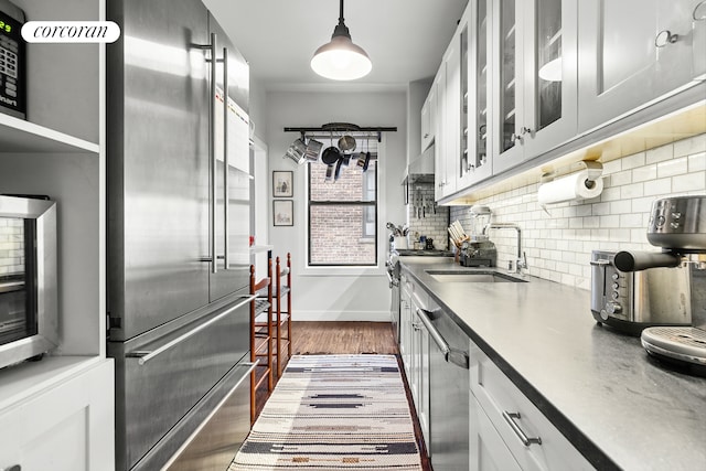 875 W 181st St Unit 6B, New York City, NY 10033 - kitchen featuring premium appliances, dark wood finished floors, a sink, decorative backsplash, and glass insert cabinets