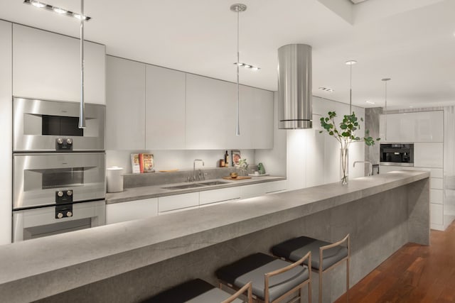9 Minetta St, New York City, NY 10012 - kitchen with a sink, modern cabinets, ventilation hood, wood finished floors, and a breakfast bar area