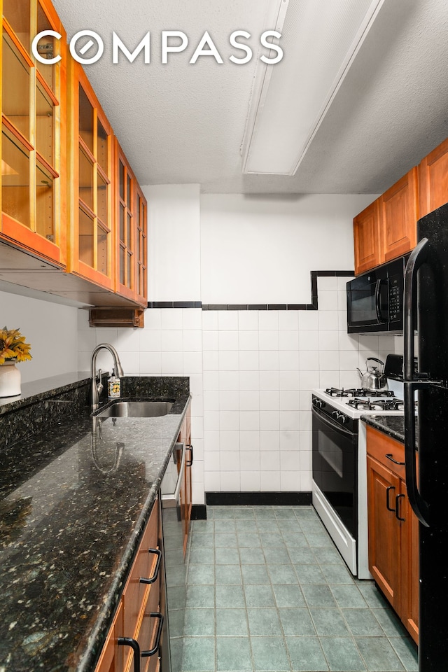 275 W 96th St Unit 12B, New York City, NY 10025 - kitchen with black appliances, a sink, tile walls, brown cabinetry, and glass insert cabinets