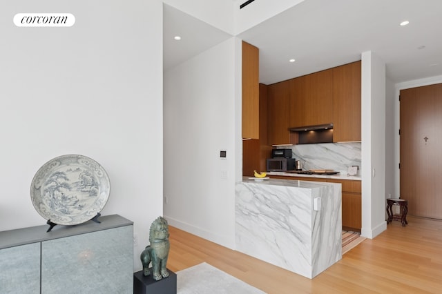 15 E 30th St Unit 22C, New York City, NY 10016 - kitchen featuring brown cabinetry, light wood-style floors, light countertops, under cabinet range hood, and recessed lighting