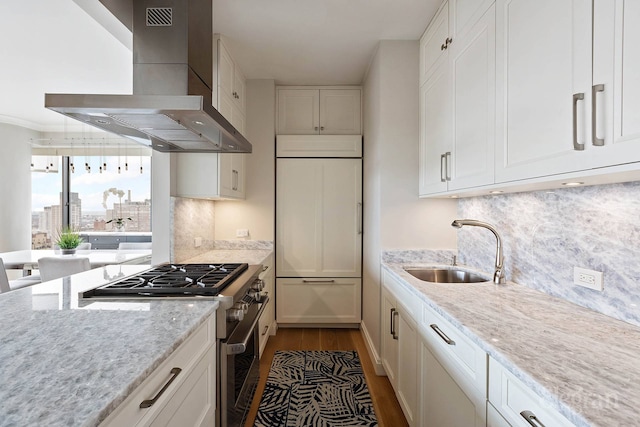 200 E 69th St Unit 28B, New York City, NY 10021 - kitchen featuring wall chimney range hood, high quality appliances, a sink, wood finished floors, and white cabinets