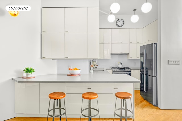 176 Johnson St Unit 2E, New York City, NY 11201 - kitchen with freestanding refrigerator, a peninsula, stainless steel range with gas cooktop, white cabinets, and light wood-type flooring