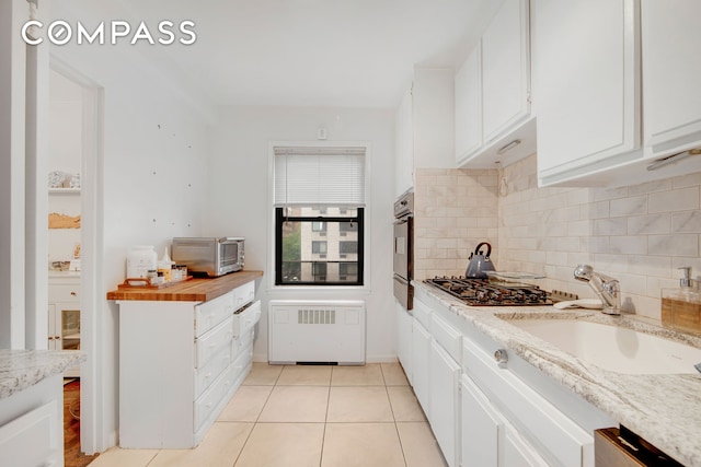301 E 48th St Unit 5D, New York City, NY 10017 - kitchen featuring backsplash, white cabinetry, gas stovetop, and light tile patterned floors