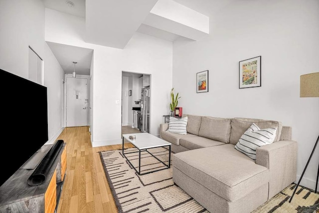 99 John St Unit 1011, New York City, NY 10038 - living room with light wood-style floors, baseboards, and a towering ceiling