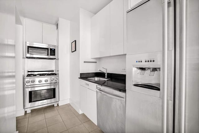99 John St Unit 1011, New York City, NY 10038 - kitchen with stainless steel appliances, a sink, dark countertops, white cabinetry, and modern cabinets