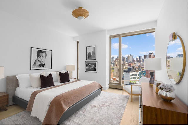 500 W 18th St Unit East15E, New York City, NY 10011 - bedroom with light wood-type flooring, a view of skyline, and access to exterior