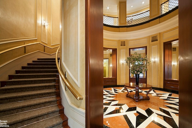 120 E 87th St Unit R14F, New York City, NY 10128 - stairs featuring inlaid floor details, a high ceiling, and a decorative wall