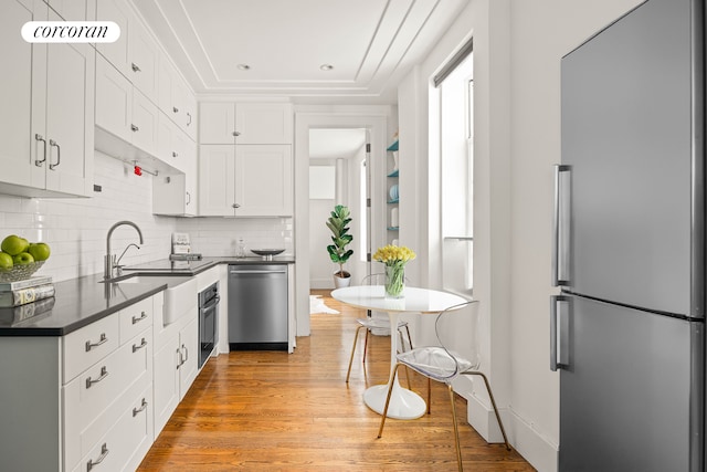 4015 7th Ave Unit 1, New York City, NY 11232 - kitchen featuring stainless steel appliances, dark countertops, white cabinetry, tasteful backsplash, and light wood-style floors