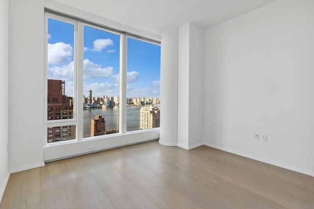 50 W St Unit 49-D, New York City, NY 10006 - empty room featuring wood finished floors, healthy amount of natural light, baseboards, and a city view