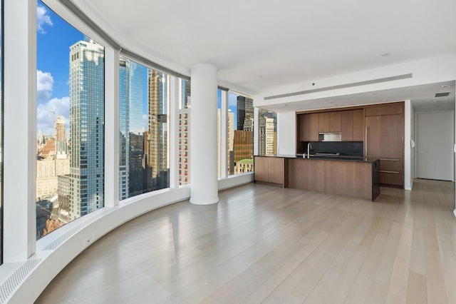 50 W St Unit 49-D, New York City, NY 10006 - unfurnished living room featuring light wood finished floors, a city view, and a sink