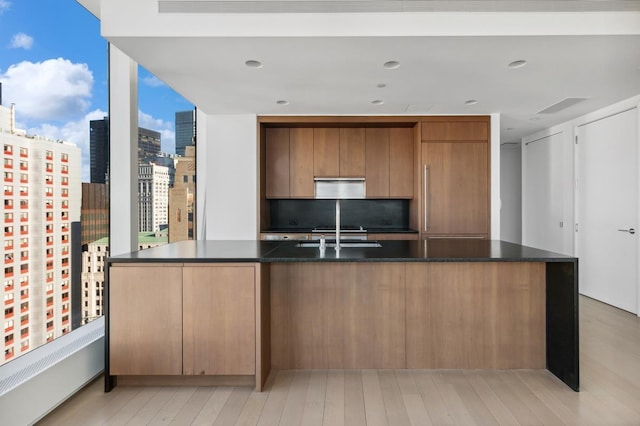 50 W St Unit 49-D, New York City, NY 10006 - kitchen with modern cabinets, light wood-type flooring, a view of city, a sink, and brown cabinetry