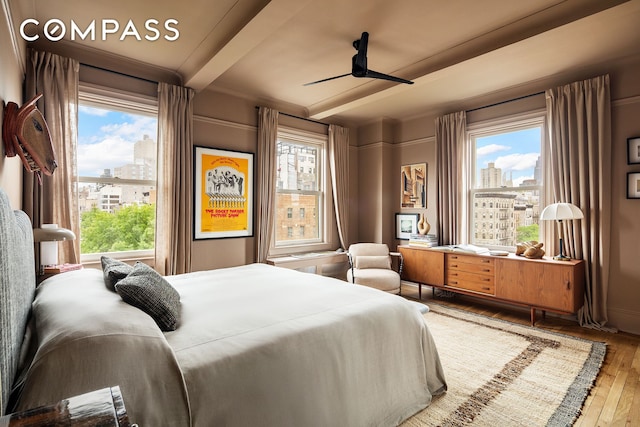 170 2nd Ave Unit 6B, New York City, NY 10003 - bedroom with hardwood / wood-style floors, multiple windows, a view of city, beam ceiling, and a ceiling fan