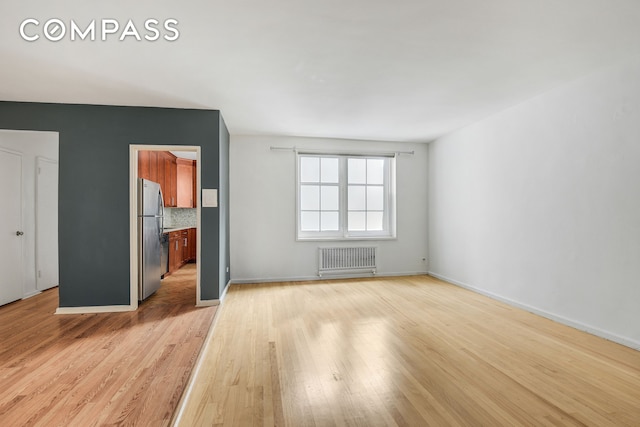 9801 Shore Rd Unit 4P, New York City, NY 11209 - empty room with radiator heating unit and light wood-style flooring