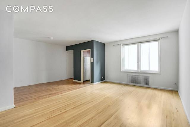 9801 Shore Rd Unit 4P, New York City, NY 11209 - empty room with radiator heating unit and light wood-style floors