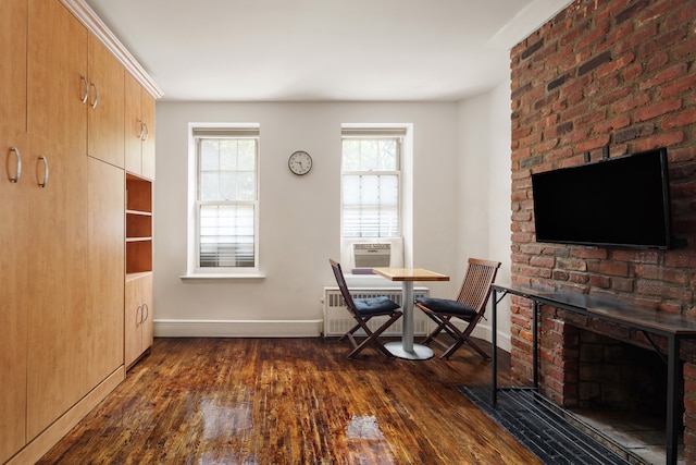 210 E 21st St Unit 2D, New York City, NY 10010 - dining area featuring dark wood-style flooring, radiator heating unit, a brick fireplace, and cooling unit