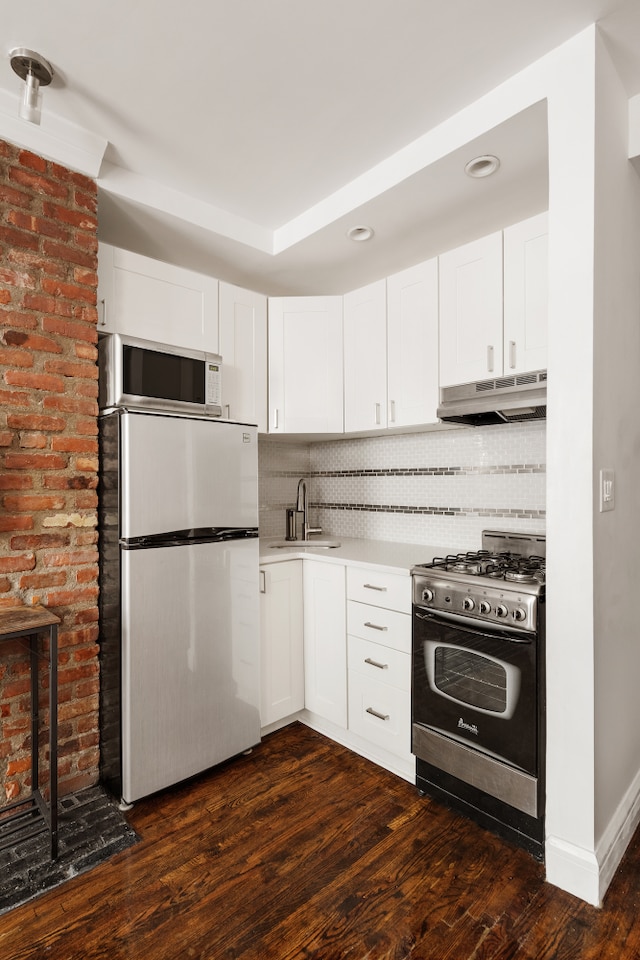 210 E 21st St Unit 2D, New York City, NY 10010 - kitchen with freestanding refrigerator, stainless steel gas range, under cabinet range hood, white microwave, and tasteful backsplash