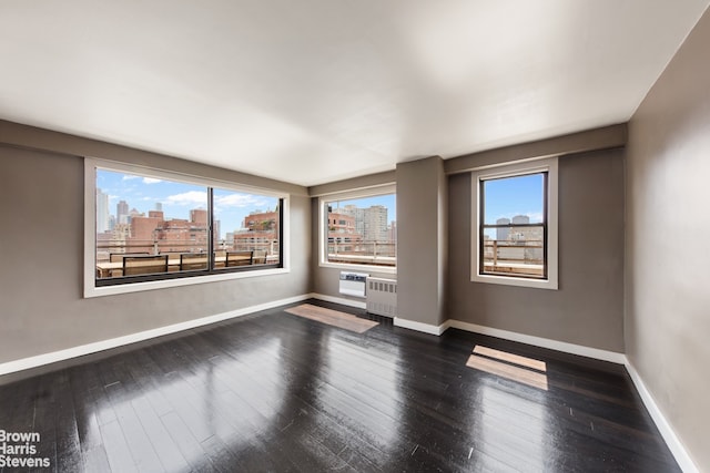 330 3rd Ave Unit 18B, New York City, NY 10010 - spare room with a view of skyline, dark wood finished floors, and radiator