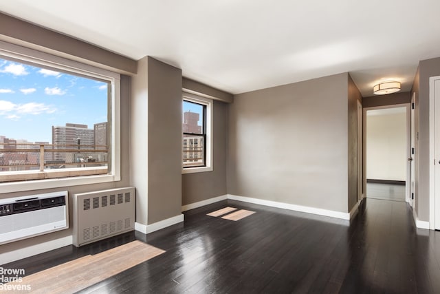 330 3rd Ave Unit 18B, New York City, NY 10010 - empty room featuring radiator, dark wood-type flooring, a city view, and a wall unit AC