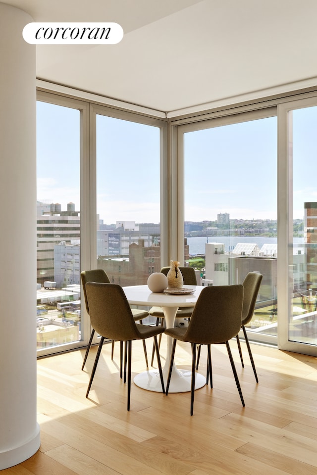 547 W 47th St Unit Ph8, New York City, NY 10036 - dining room featuring light wood-type flooring, a city view, and a wall of windows