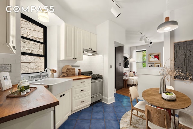 41 Perry St Unit 2A, New York City, NY 10014 - kitchen with wood counters, stainless steel gas stove, track lighting, under cabinet range hood, and tasteful backsplash