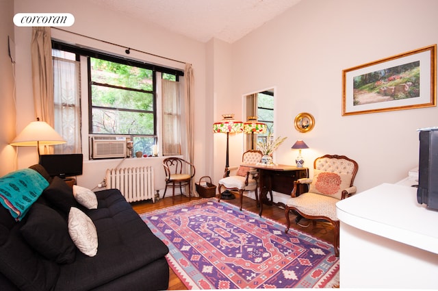 140 W 69th St Unit 26C, New York City, NY 10023 - living area featuring radiator, wood finished floors, cooling unit, and lofted ceiling