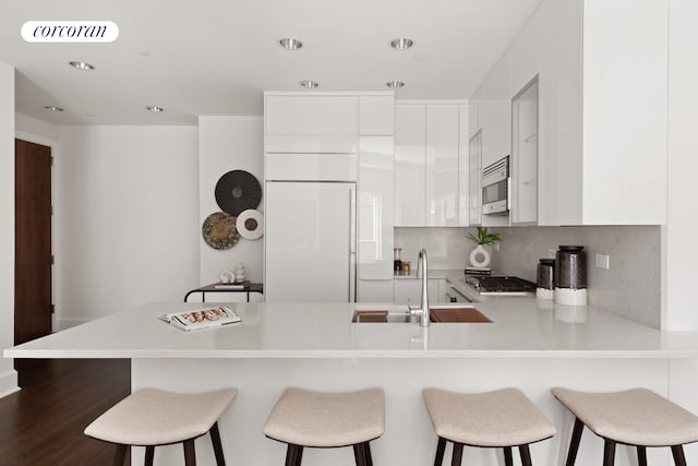 250 E 49th St Unit 3D, New York City, NY 10017 - kitchen with a peninsula, modern cabinets, white cabinets, light countertops, and recessed lighting