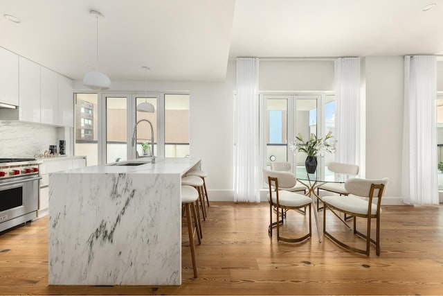 427 E 90th St Unit Penthouse9, New York City, NY 10128 - kitchen featuring designer range, modern cabinets, white cabinets, a kitchen breakfast bar, and a center island with sink