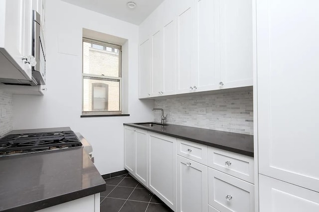 25 5th Ave Unit 14B, New York City, NY 10003 - kitchen featuring tasteful backsplash, white cabinets, dark tile patterned flooring, and stainless steel microwave
