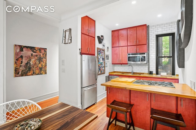 223 W 21st St Unit 1M, New York City, NY 10011 - kitchen featuring stainless steel appliances, butcher block counters, light wood-style flooring, tasteful backsplash, and recessed lighting