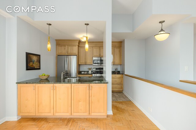 393 W 49th St Unit 5C, New York City, NY 10019 - kitchen with appliances with stainless steel finishes, light brown cabinetry, a peninsula, and dark stone counters