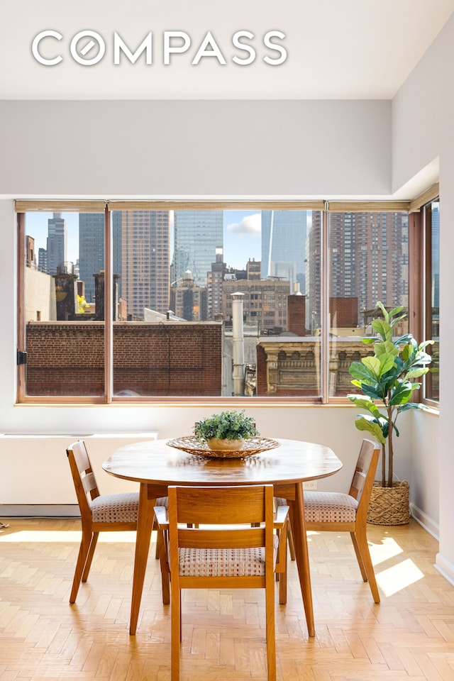 393 W 49th St Unit 5C, New York City, NY 10019 - dining room featuring a skyline view and baseboards