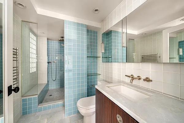 227 E 57th St Unit 12Eg, New York City, NY 10022 - bathroom featuring tile walls, a stall shower, vanity, tile patterned flooring, and a towel warmer