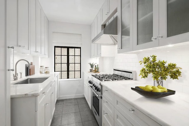 227 E 57th St Unit 12Eg, New York City, NY 10022 - kitchen with stainless steel range, under cabinet range hood, backsplash, white cabinets, and glass insert cabinets