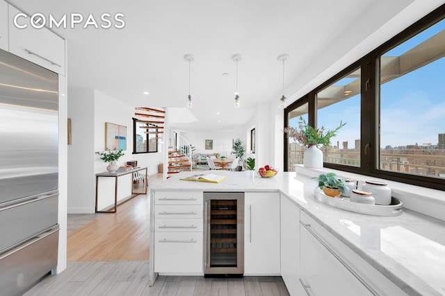 136 E Broadway Pha, Pha, New York City, NY 10002 - kitchen with built in refrigerator, beverage cooler, white cabinets, a peninsula, and light stone countertops