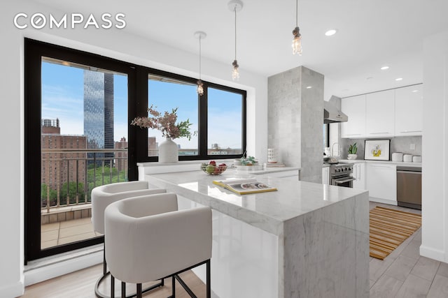 136 E Broadway Pha, Pha, New York City, NY 10002 - kitchen with modern cabinets, white cabinetry, a peninsula, wall chimney range hood, and stainless steel appliances
