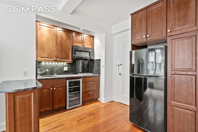 155 E 49th St Unit 8C, New York City, NY 10017 - kitchen with freestanding refrigerator, wine cooler, black microwave, light wood-style flooring, and decorative backsplash